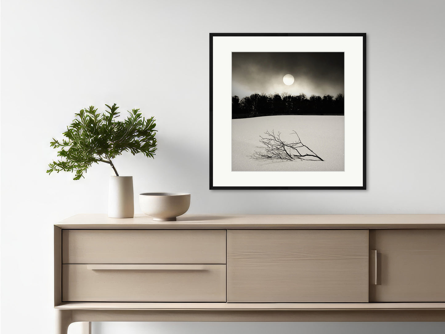 Soulscapes 2 by Andrea Christl, a tranquil black-and-white art photography print of a lone branch resting in a snowy landscape with a forest in the background, framed with a passe-partout.